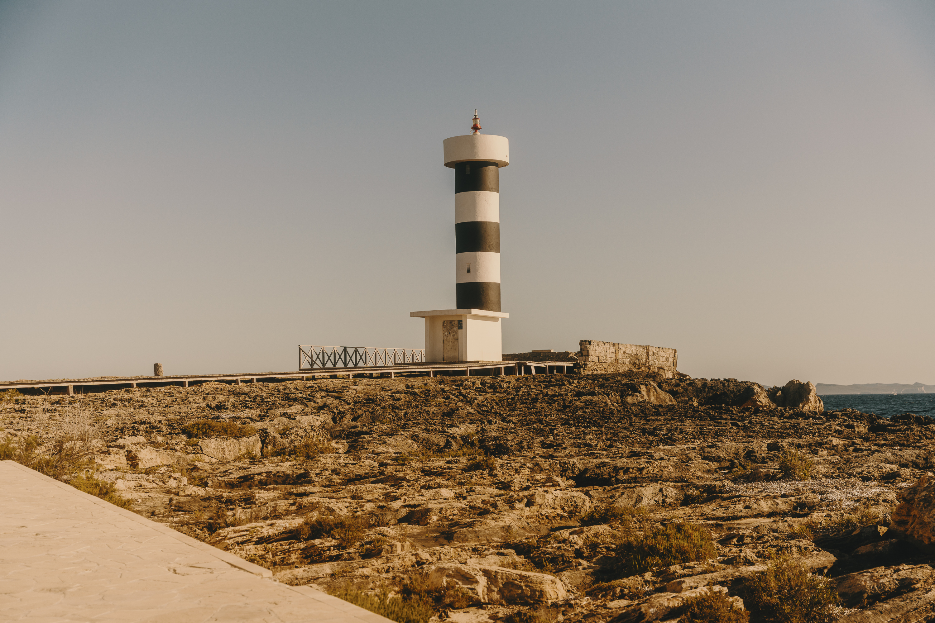 Striped lighthouse on rocky coastal landscape