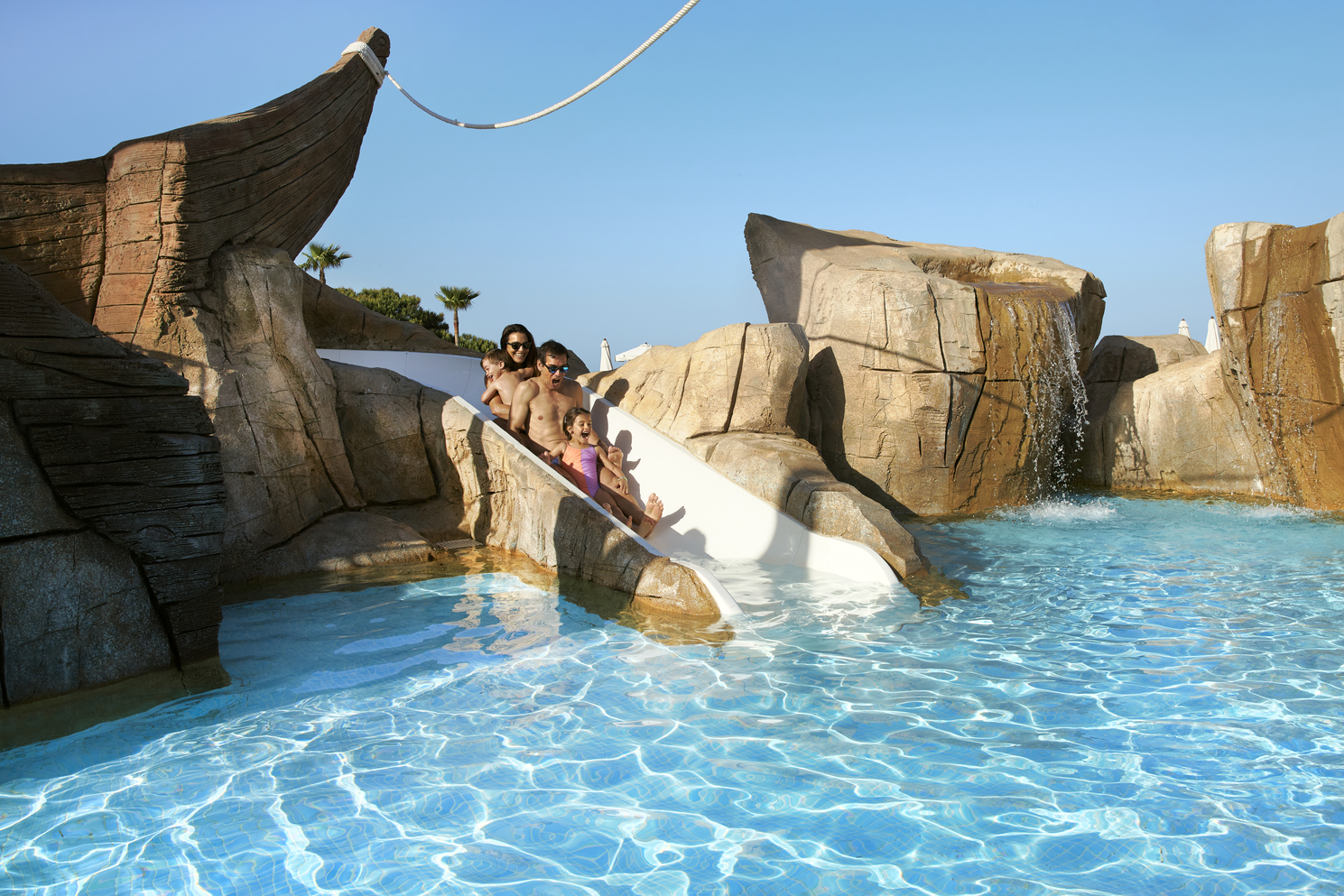 Family enjoying waterslide at resort pool