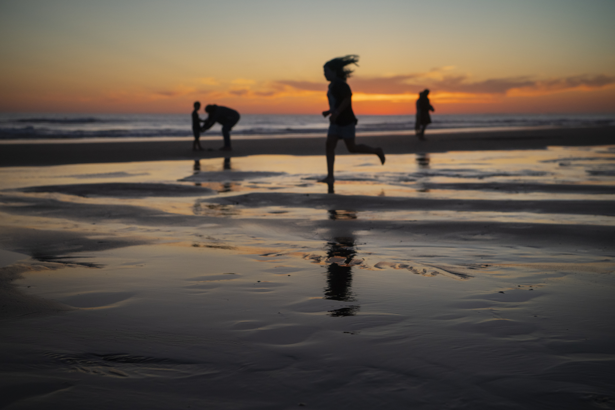 Children playing on beach at sunset