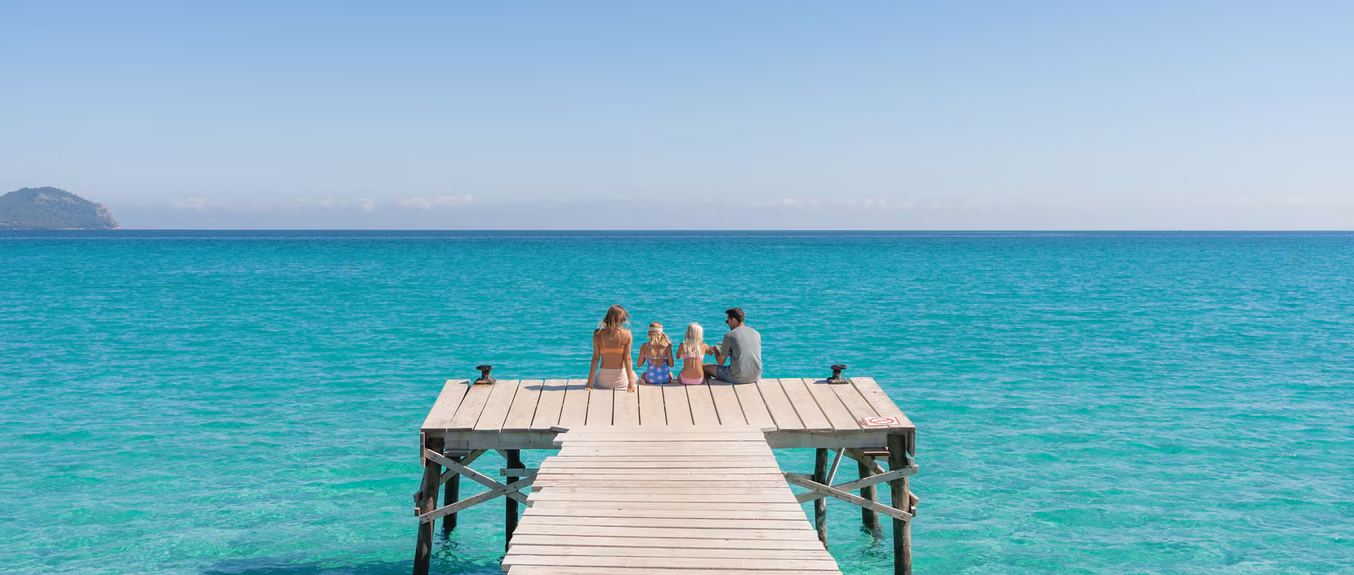 Family Relaxing on Wooden Pier Over Turquoise Sea